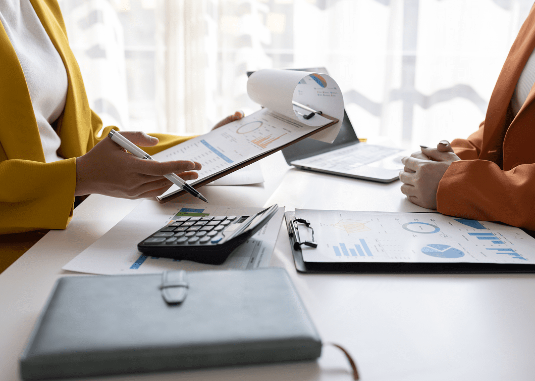 People working with documents, calculator, and laptop in a bright office.